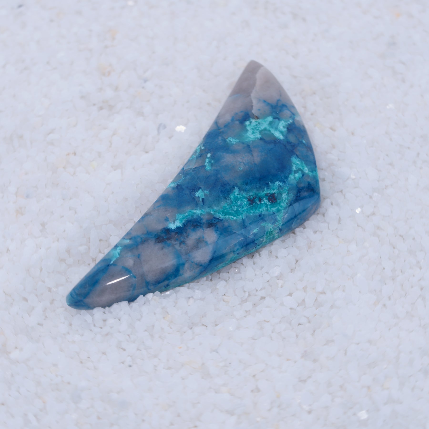 Dark blue Papagoite-bearing polished Canyonite gemstone on a light background