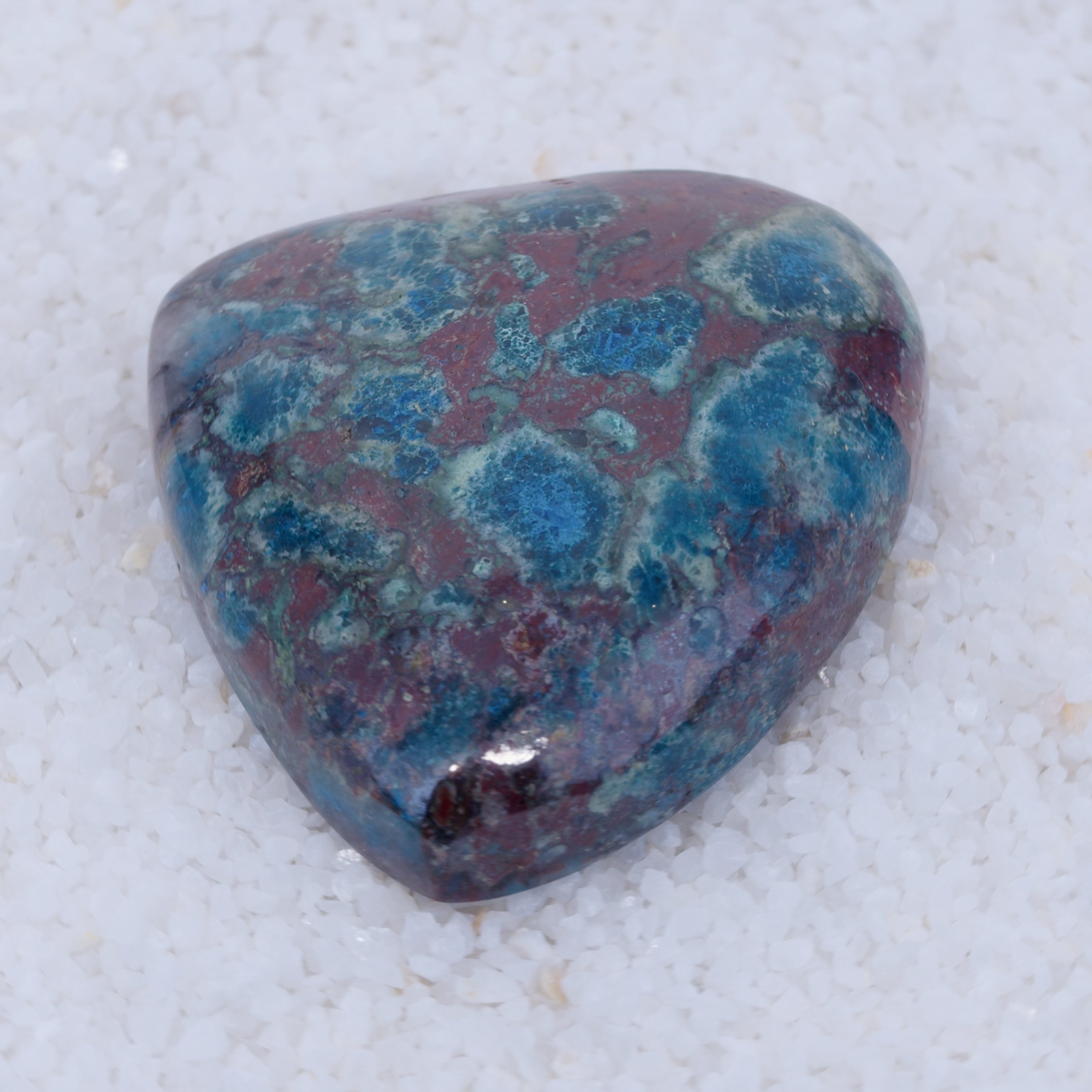 Triangular Canyonite gemstone with blue and purple patterns on a white background