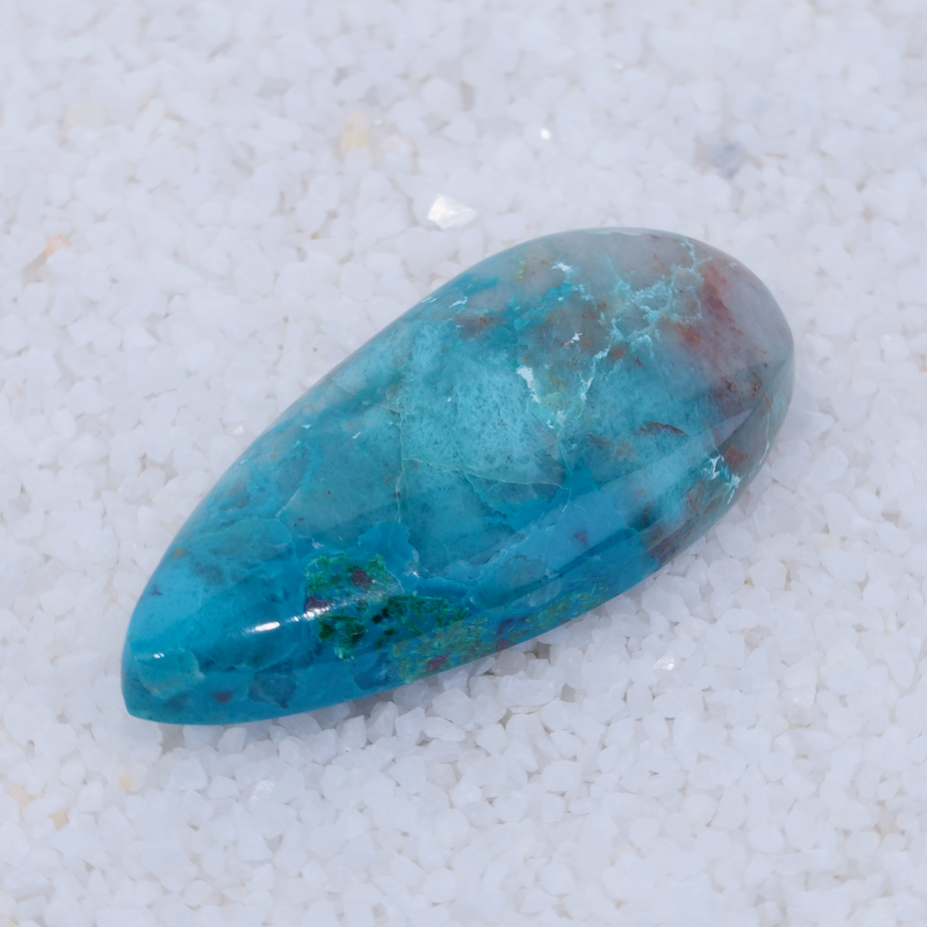 Turquoise stone on a white sand background