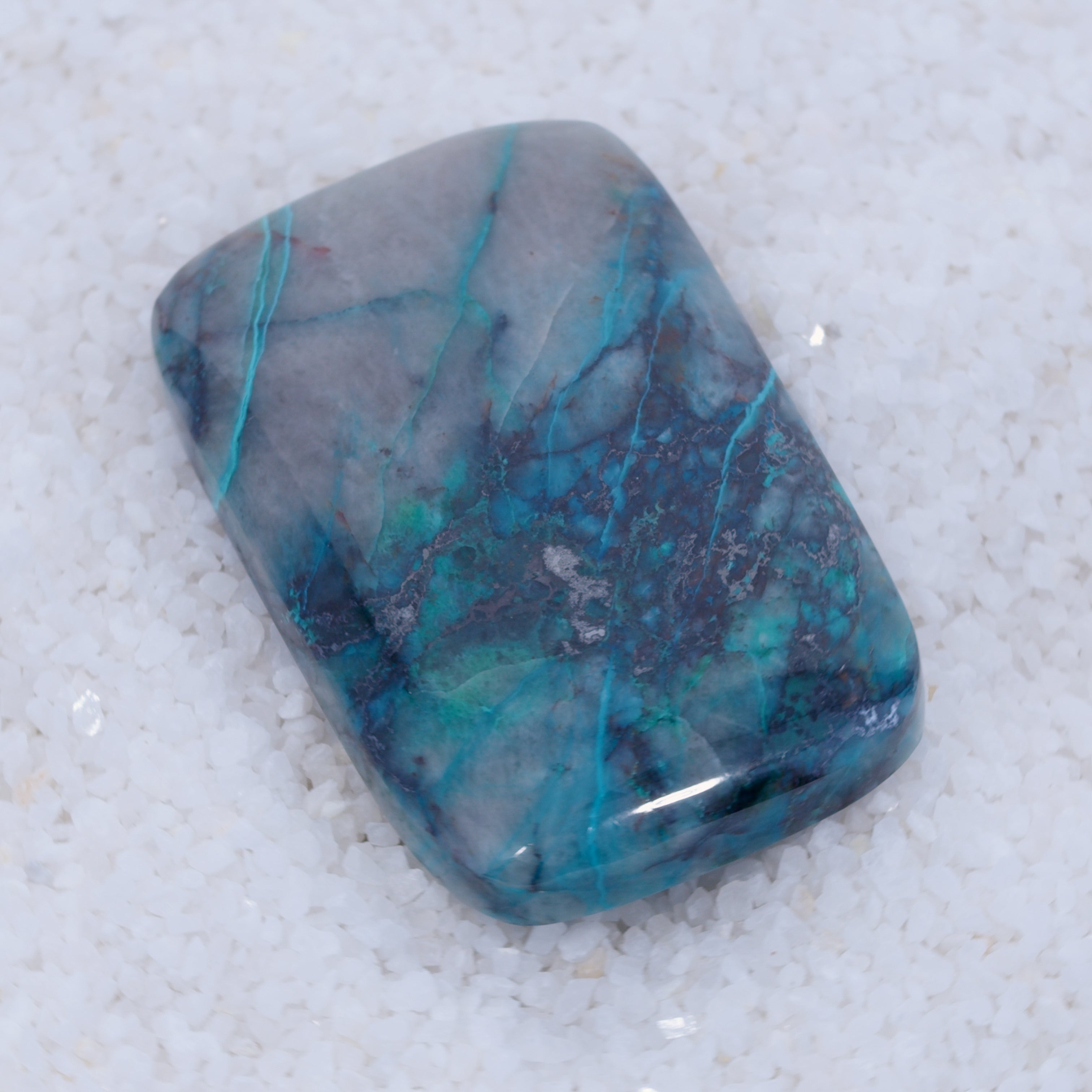 Polished Canyonite gemstone with blue and gray marbled pattern on a white background