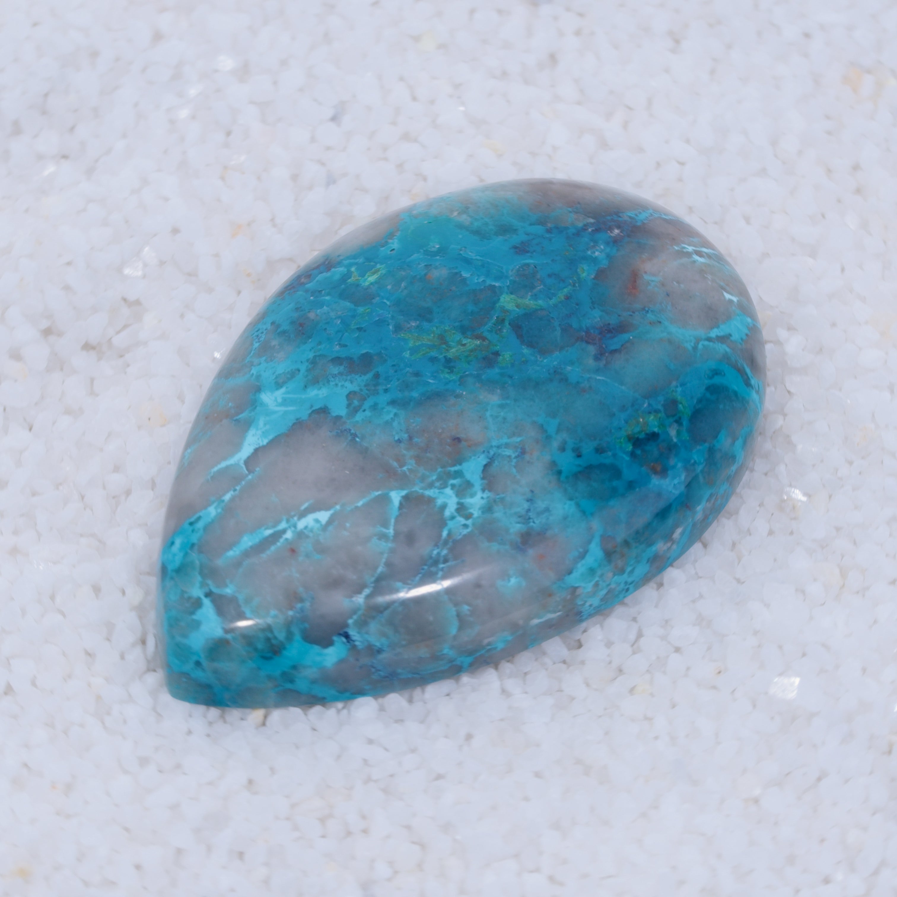 Teardrop-shaped turquoise colored Canyonite stone on a light gray background