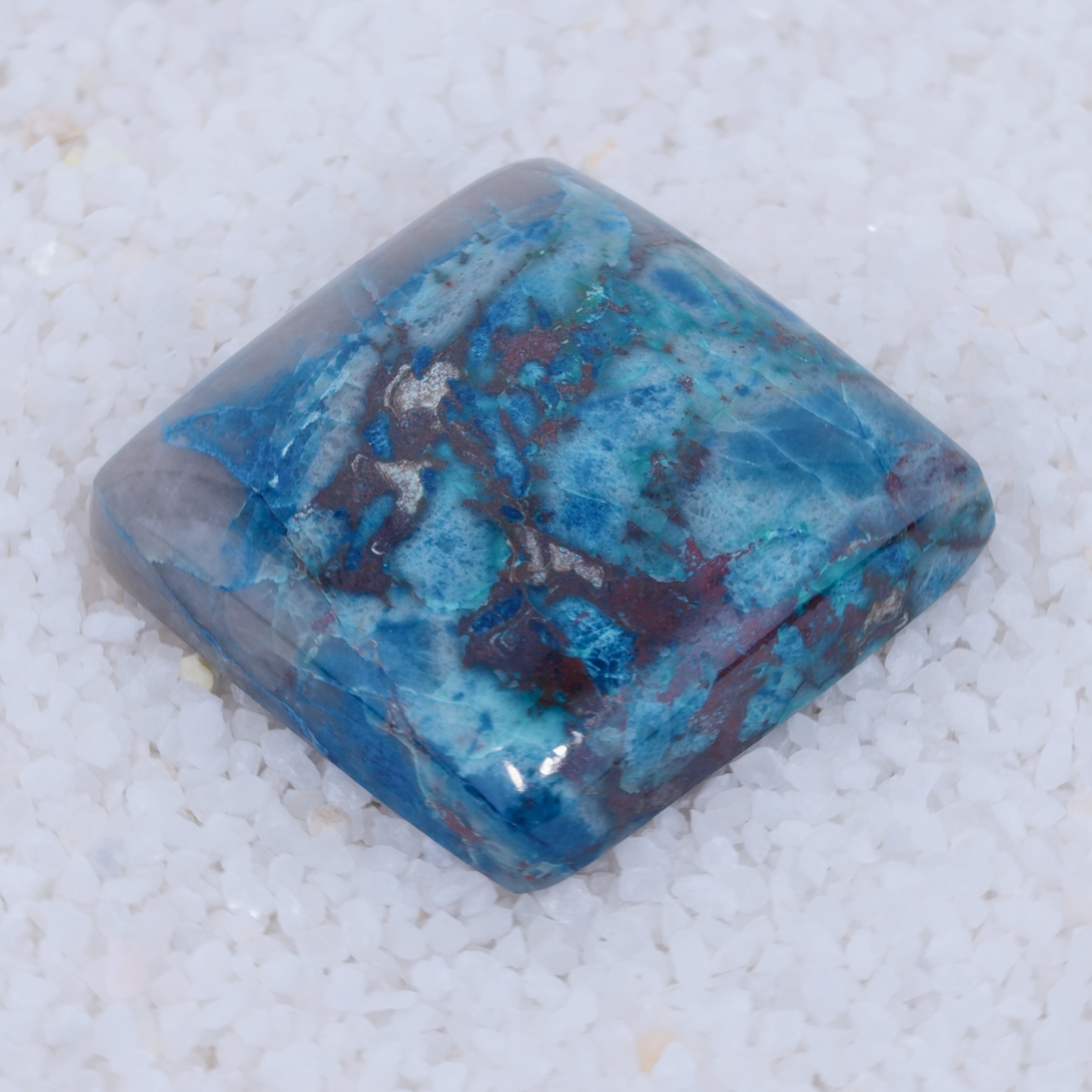 Blue and purple Canyonite stone on a white sandy background
