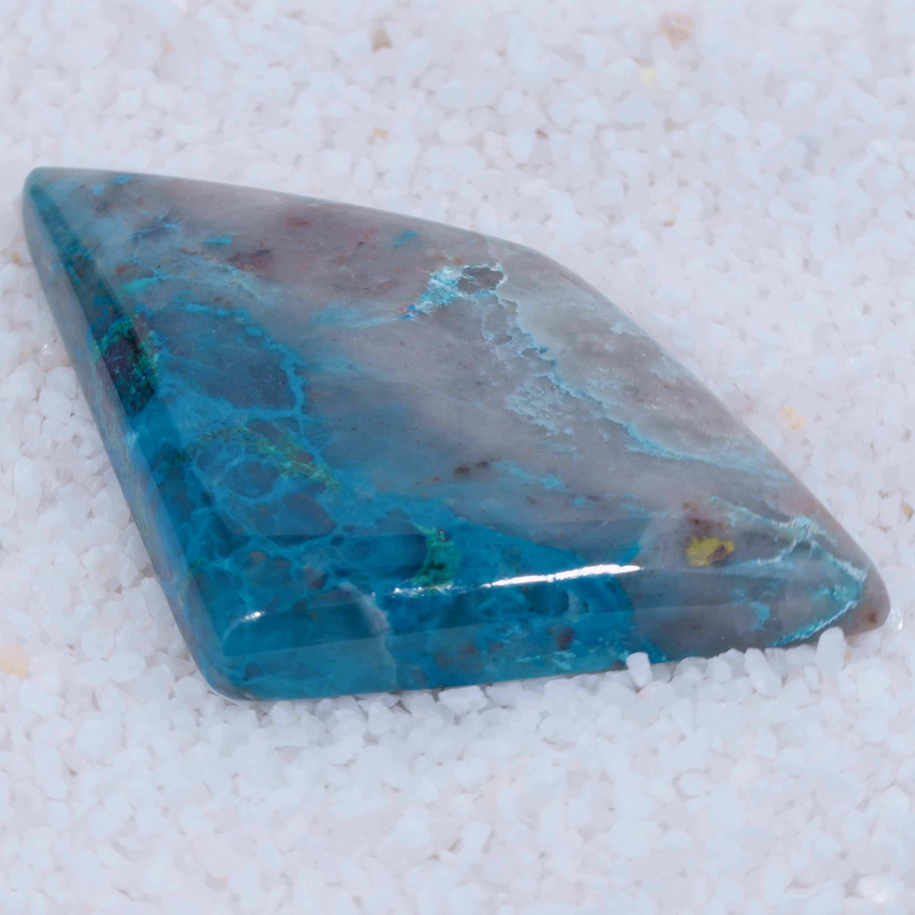 Canyonite Teardrop-shaped blue stone on a white sandy background