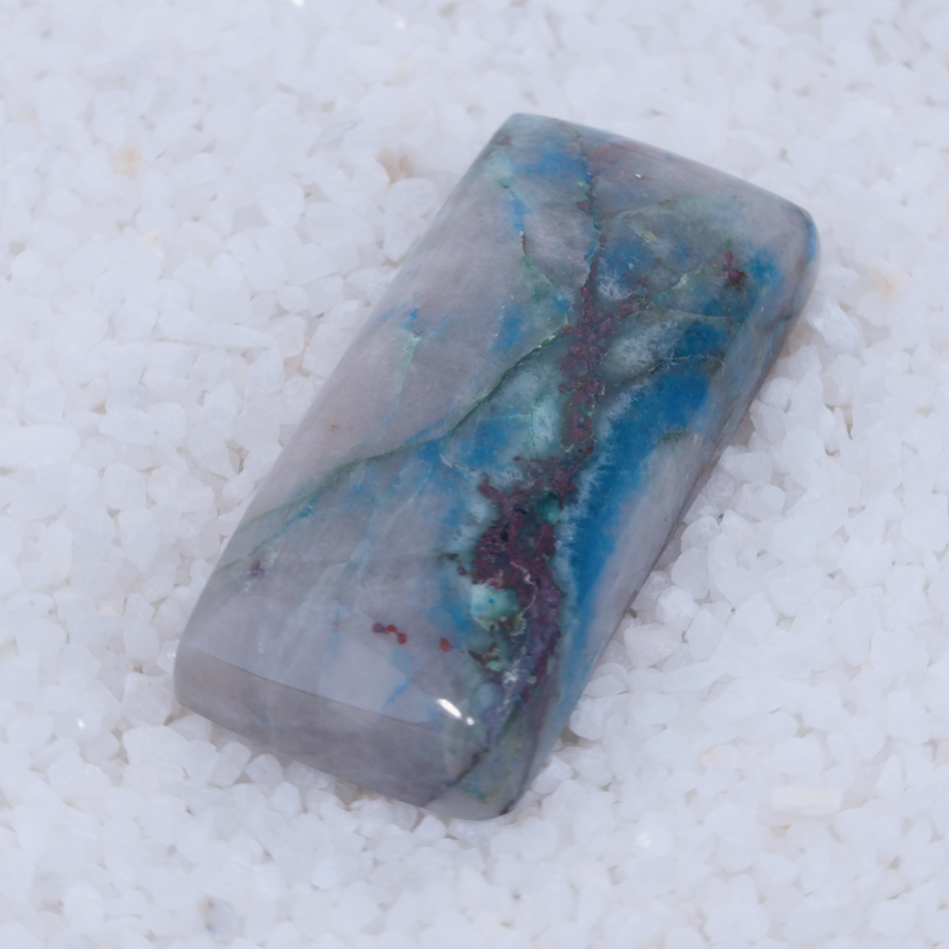 Polished Canyonite stone with blue and purple vein on a white background