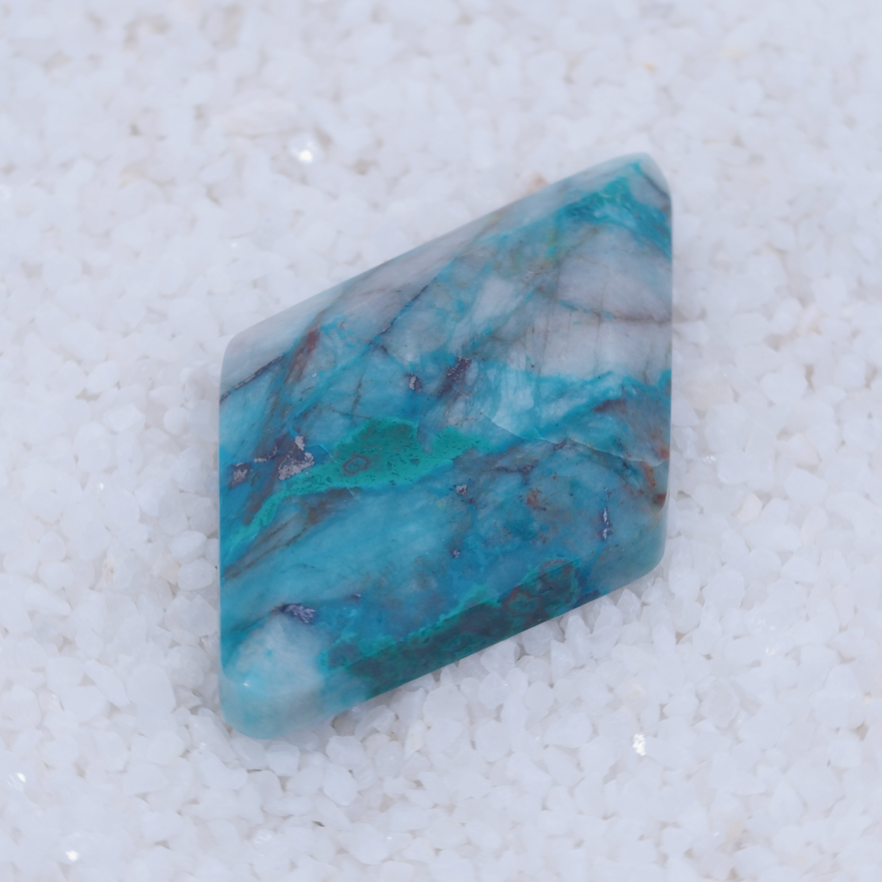 Turquoise colored Canyonite stone on a white background