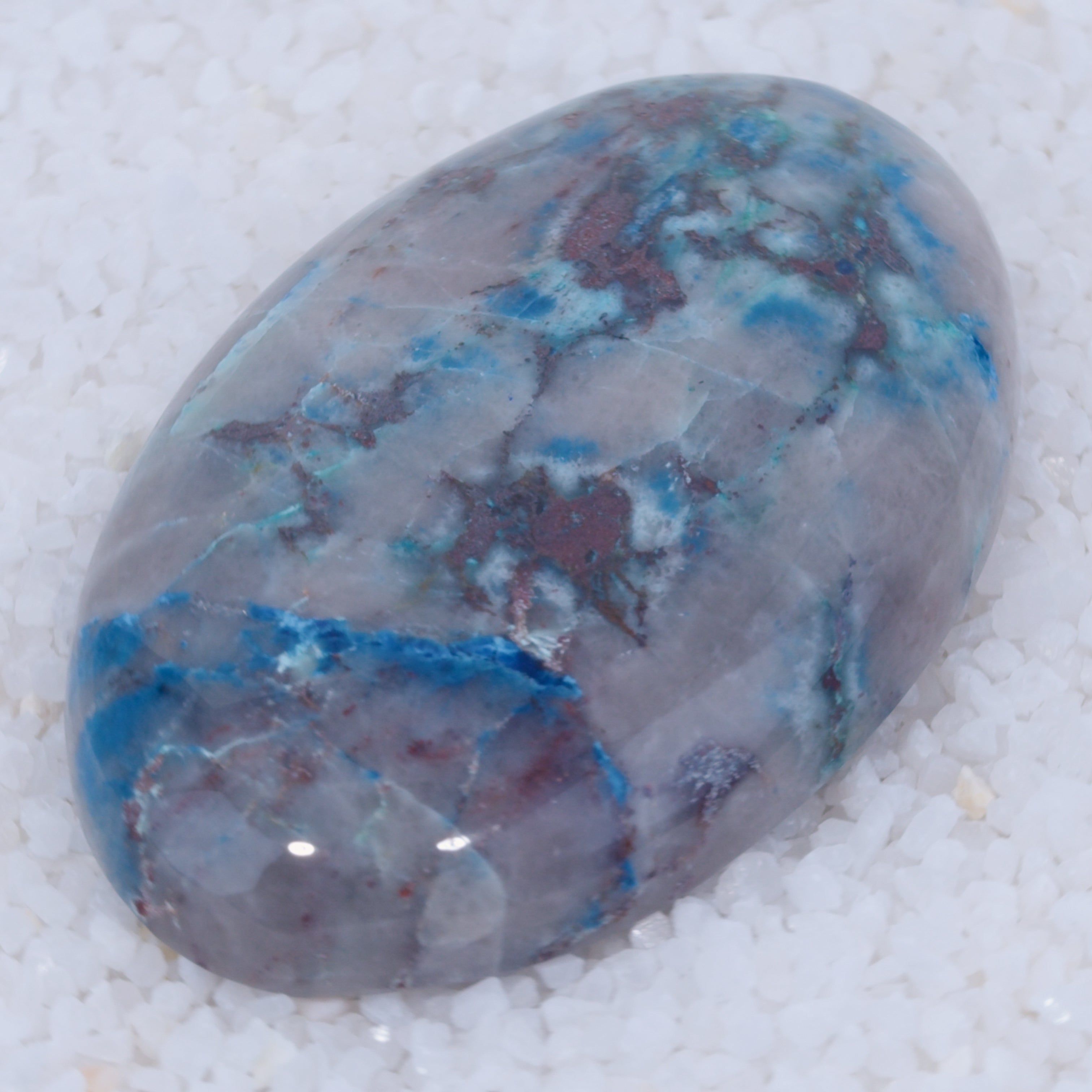 Polished Canyonite stone with blue and purple patterns on a textured white background