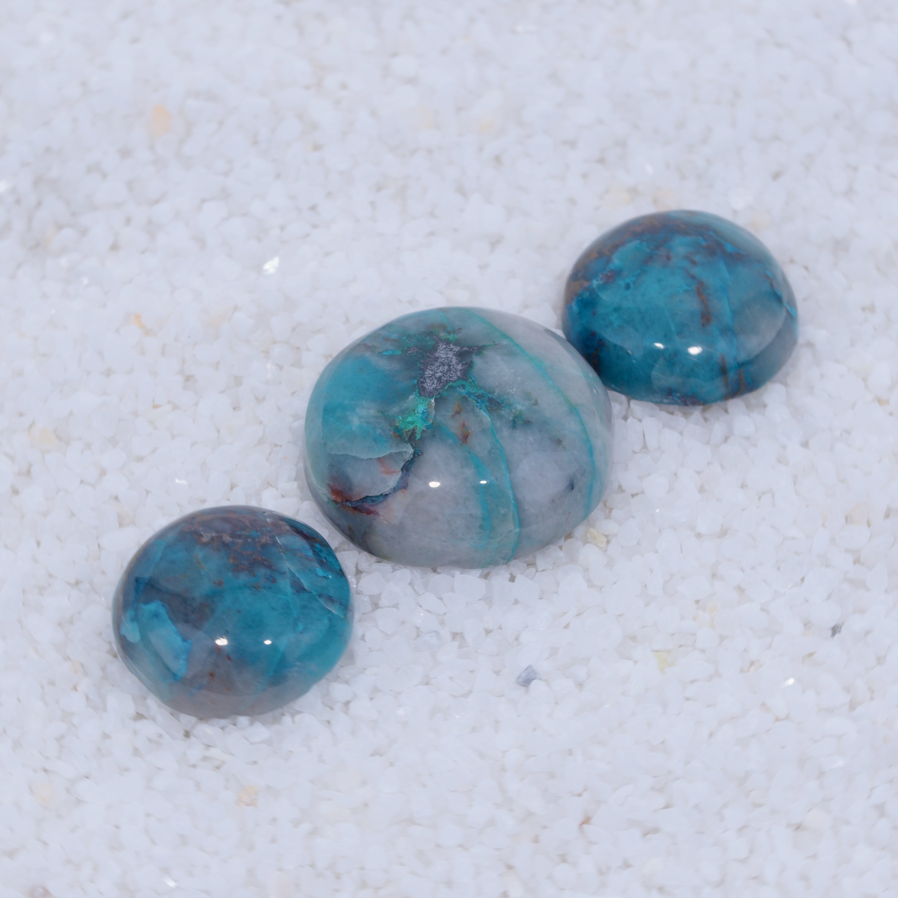 Three marbled blue and gray stones on a textured white surface