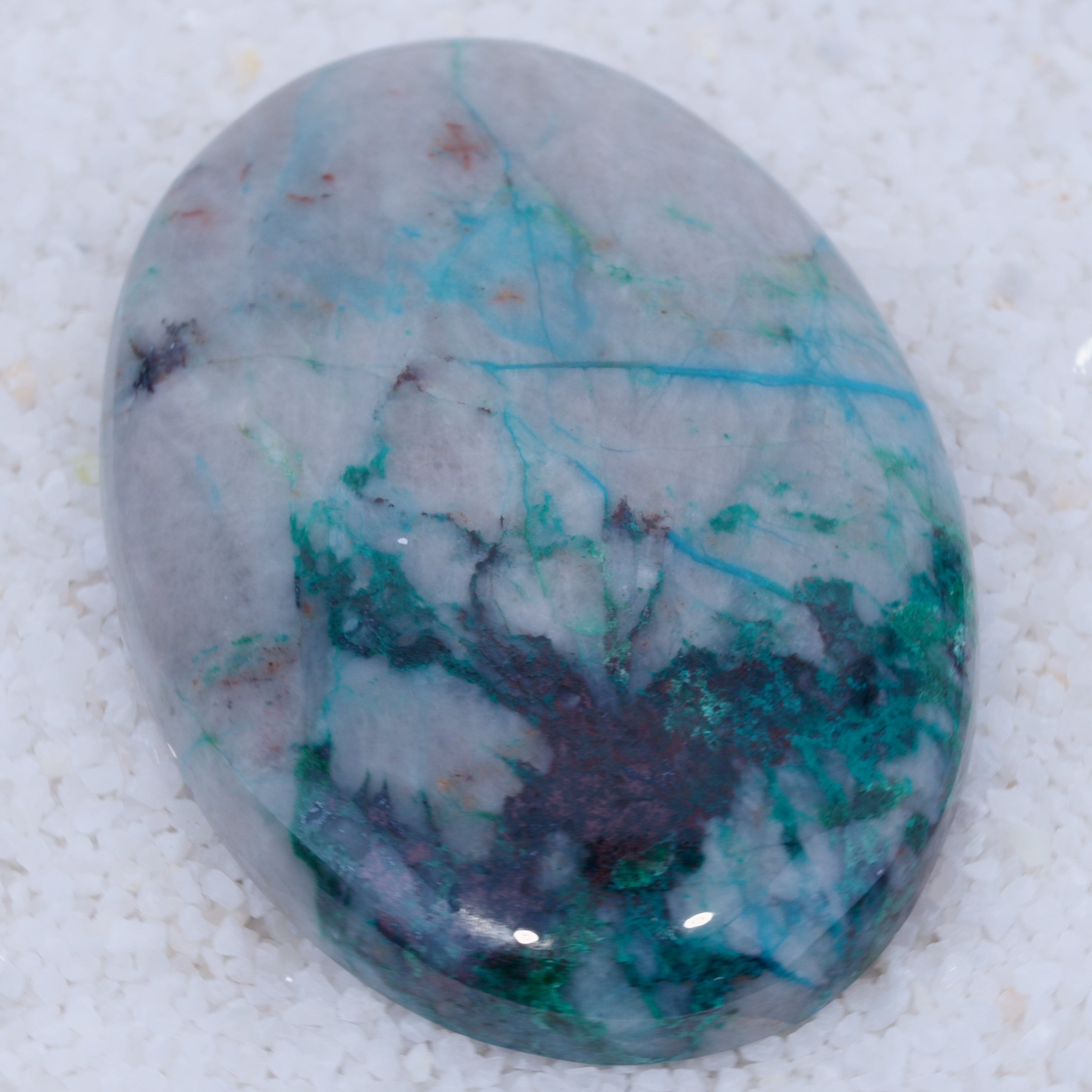 Polished Canyonite gemstone with blue and green veins on a white background