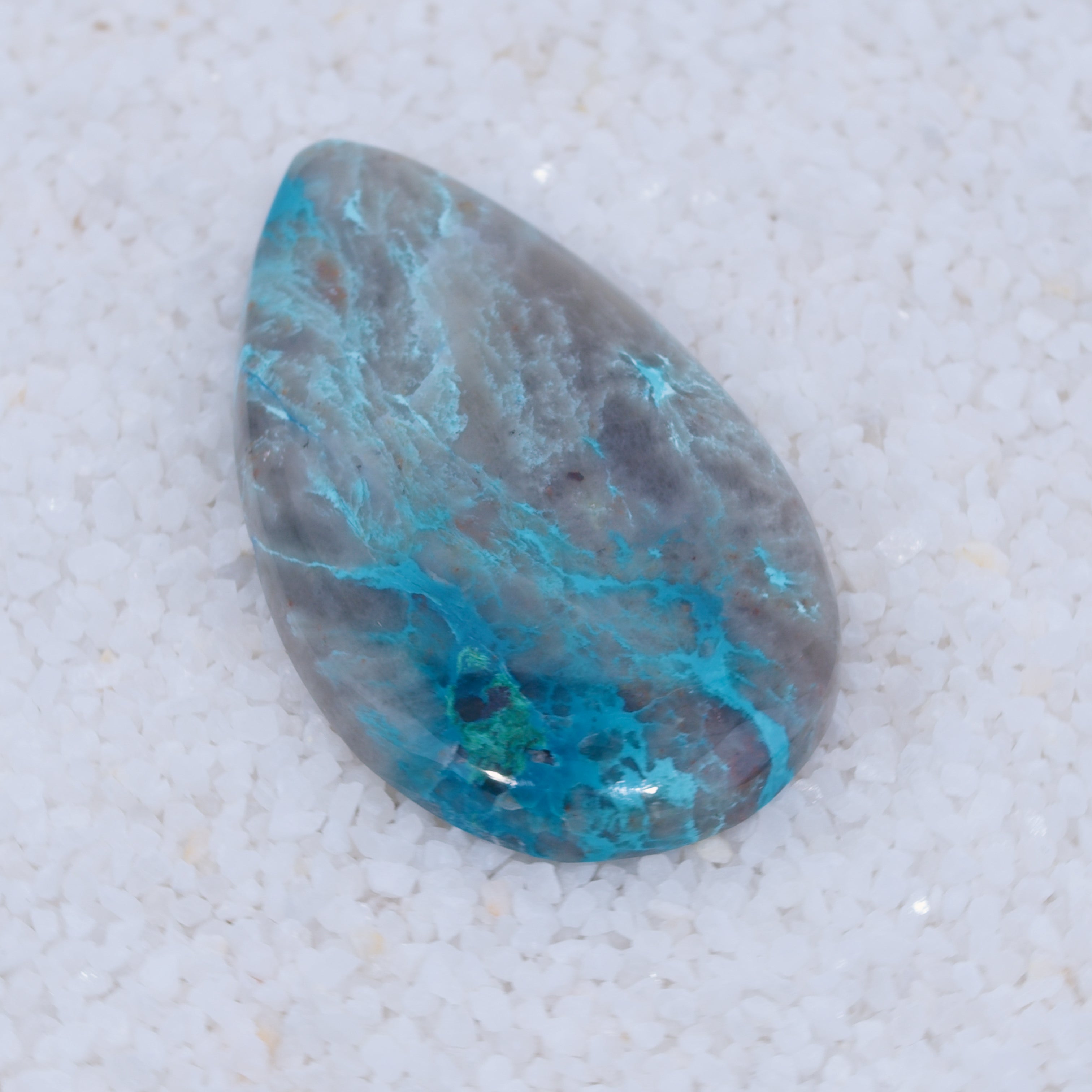 Teardrop-shaped stone with blue and green patterns on a light gray background