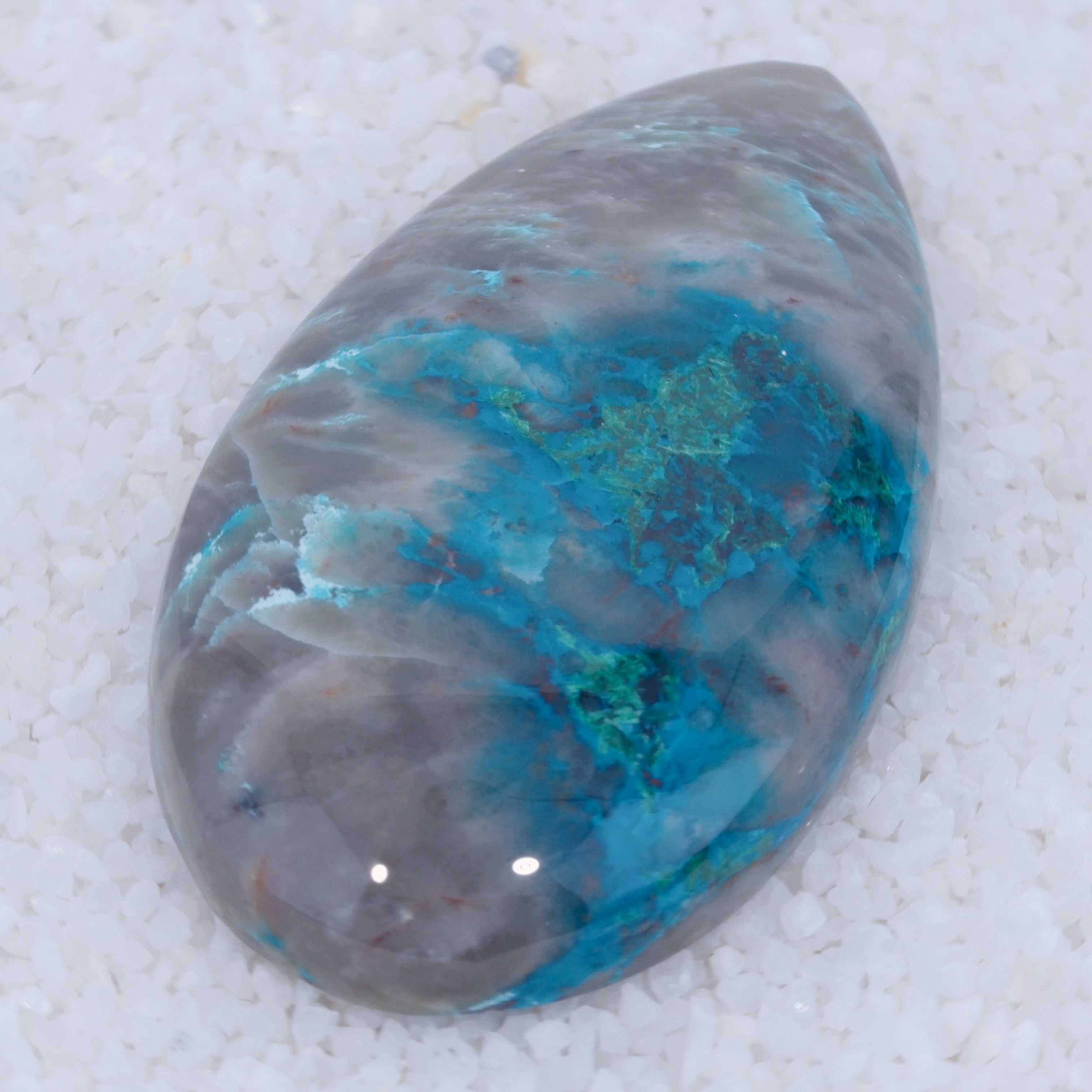 Teardrop-shaped Canyonite stone with blue and gray patterns on a white background