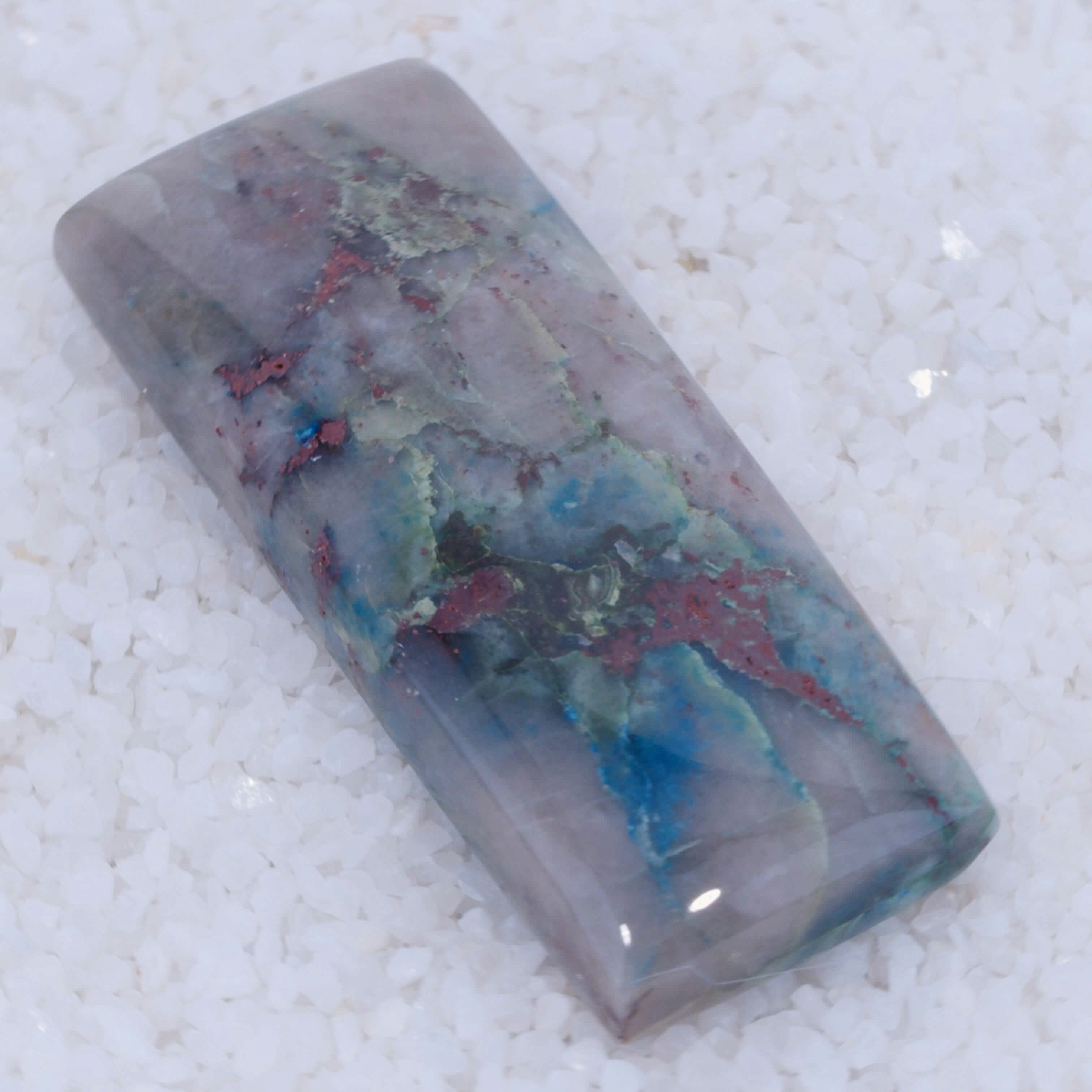 Polished Canyonite stone with multicolored patterns on a textured white background