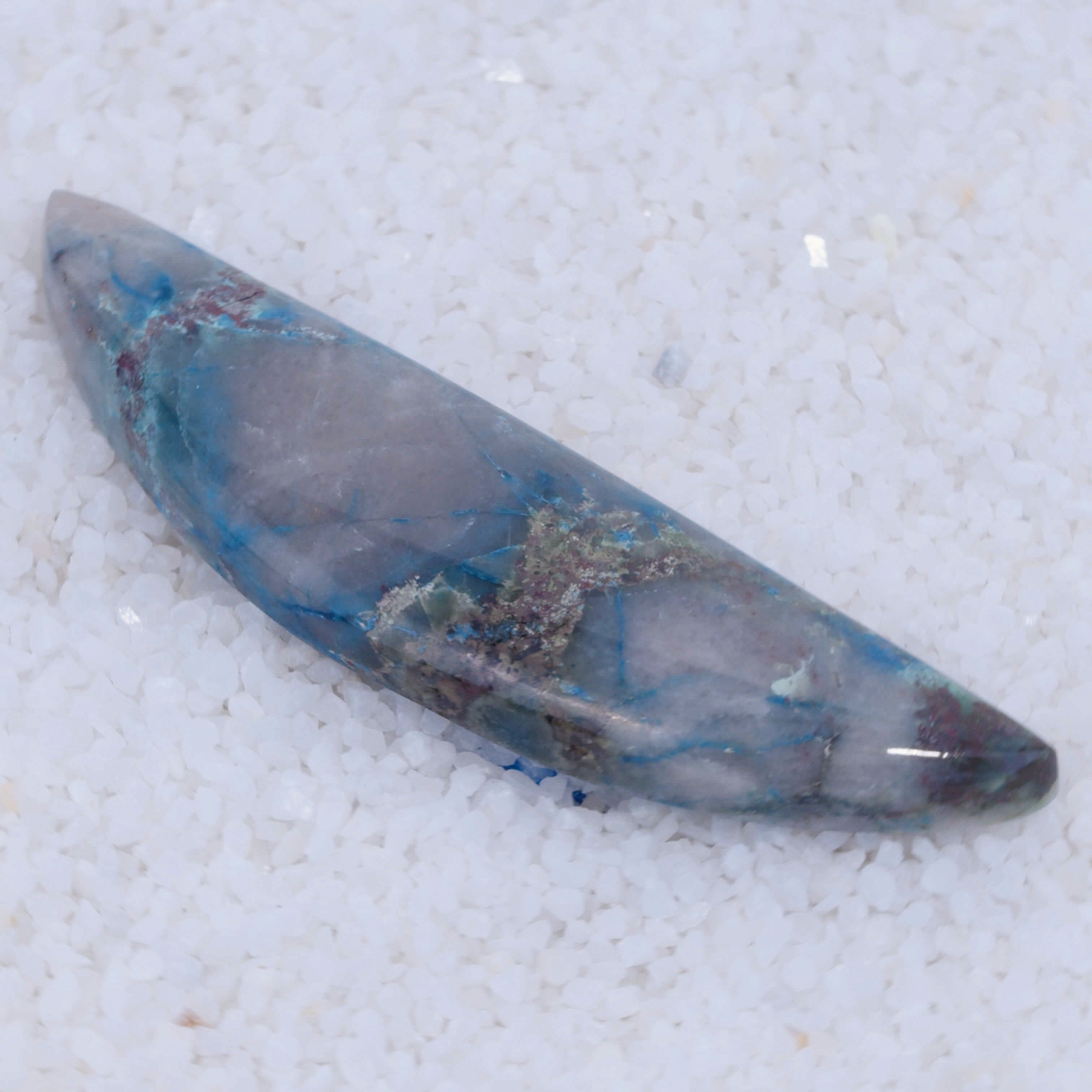 Polished stone with blue and gray patterns on a textured white background
