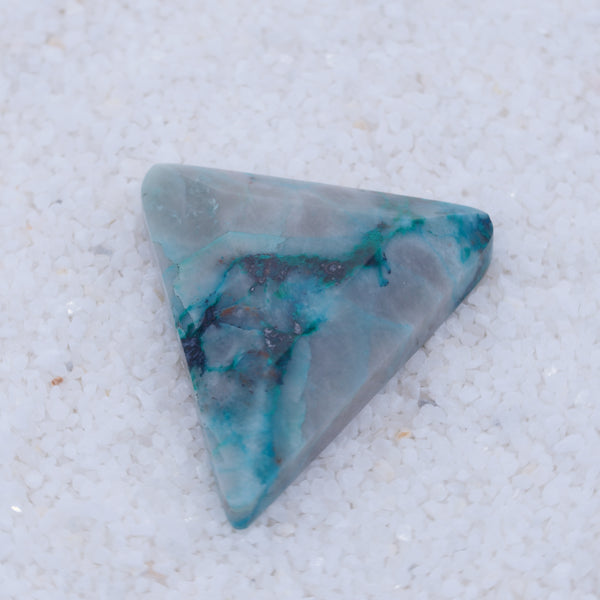 Triangular turquoise stone on a textured white background