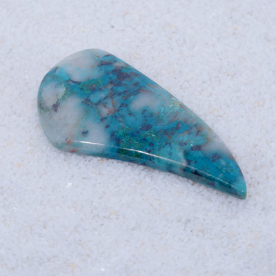 Teardrop-shaped turquoise stone on a textured white background