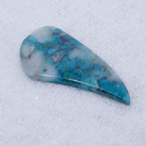 Teardrop-shaped turquoise stone on a textured white background