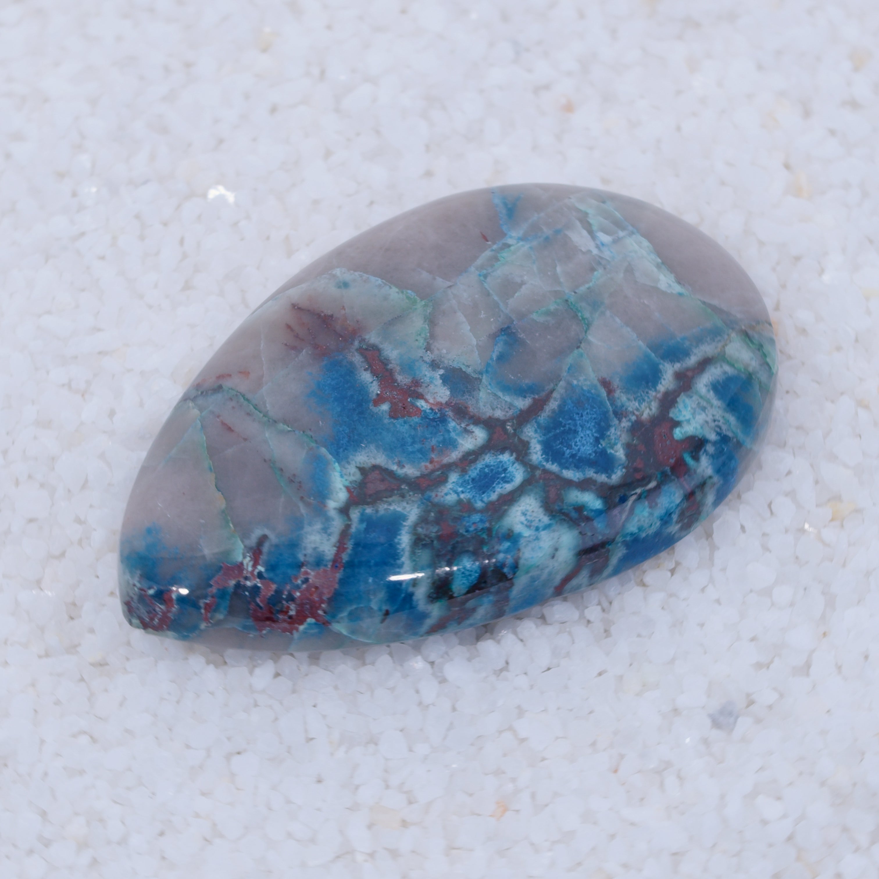 Polished Canyonite gemstone with blue and red patterns on a white background