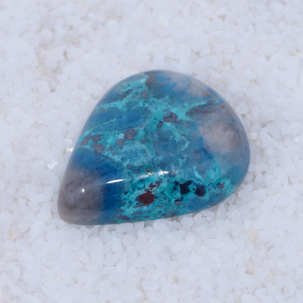 Turquoise stone with purple and red patterns on a white background