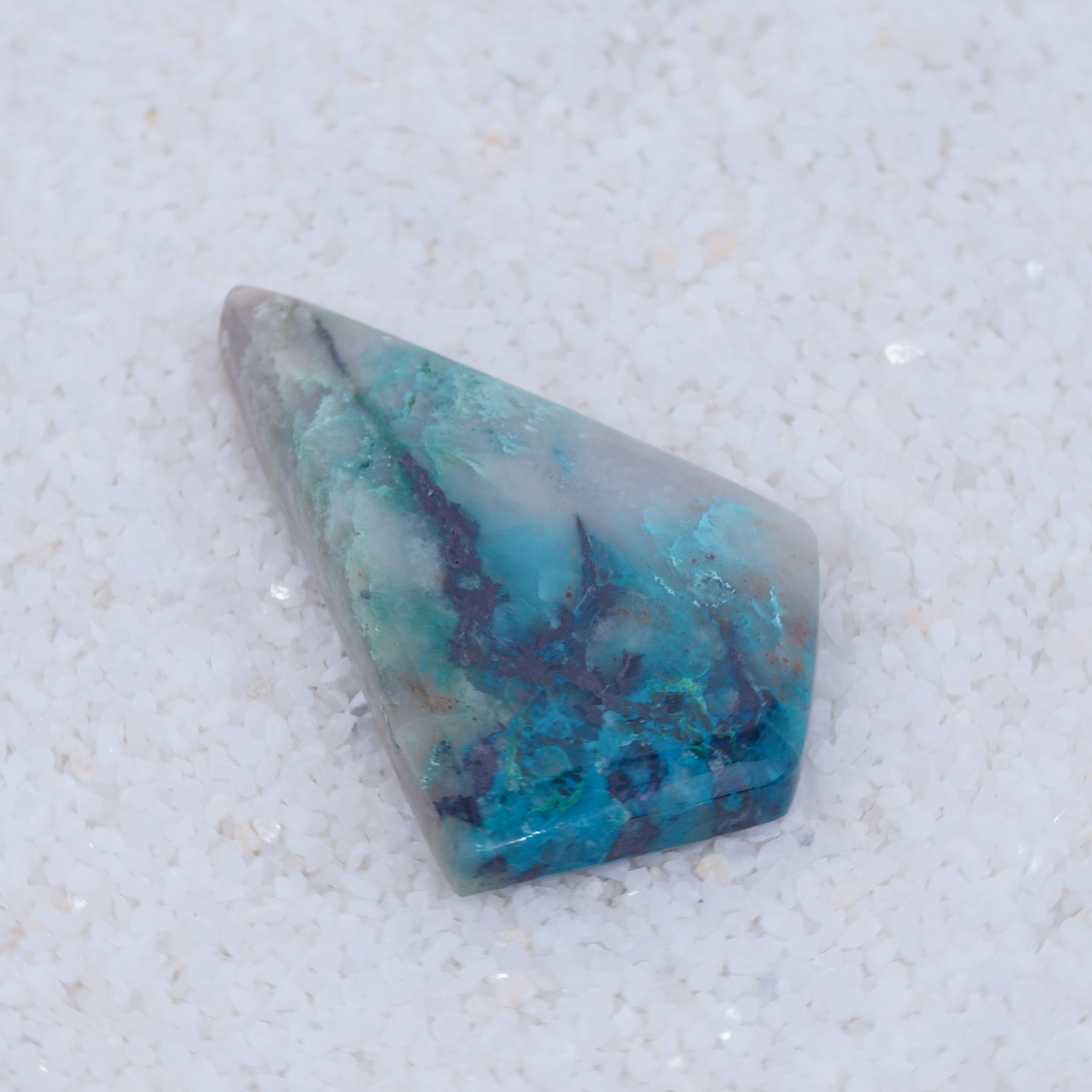 Turquoise colored Canyonite stone with purple veins on a white background