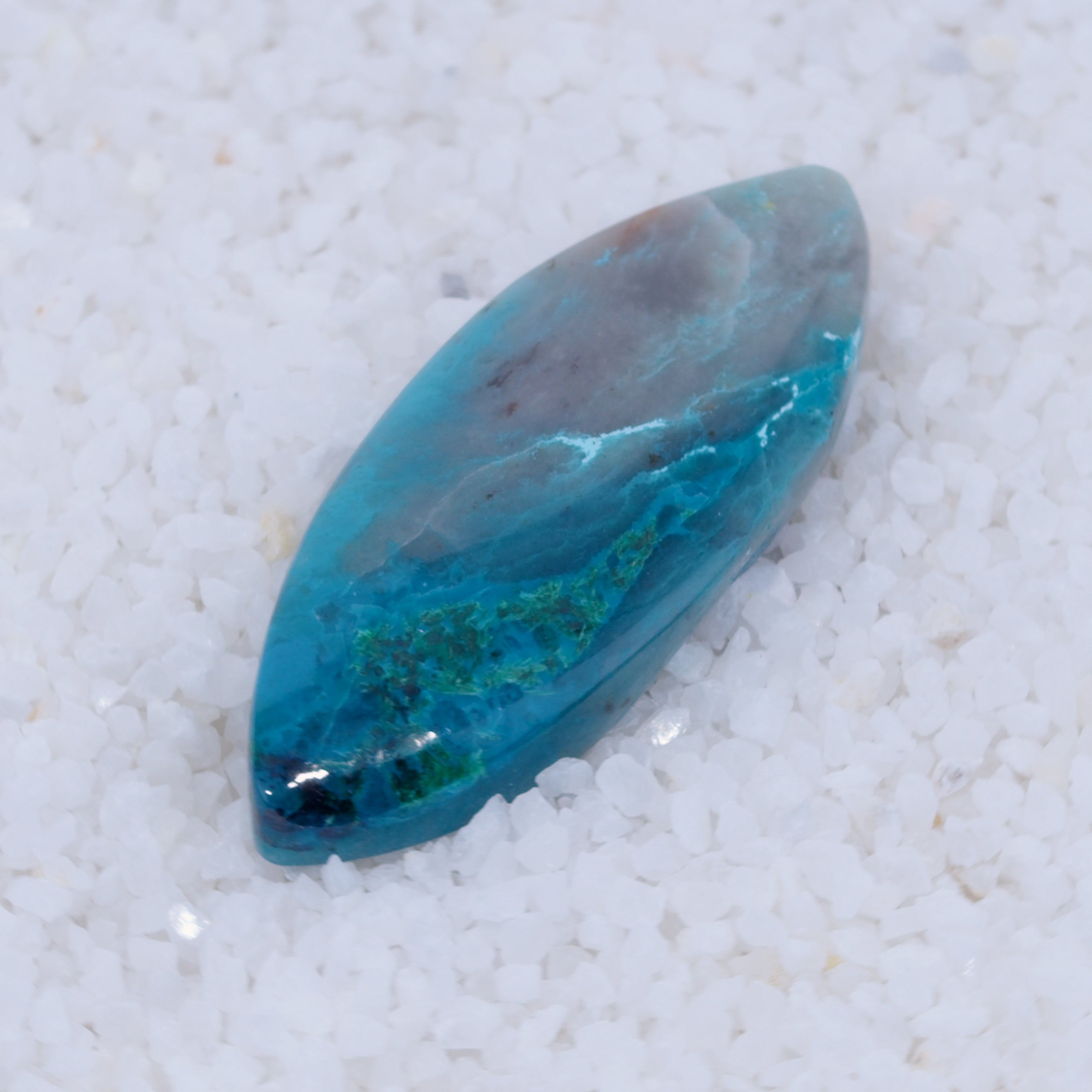 Teal colored Canyonite stone with green flecks on a white textured background