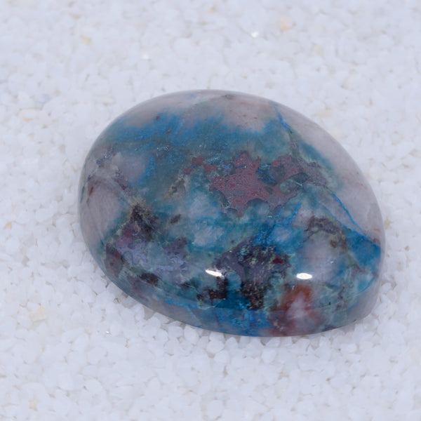 Polished Canyonite gemstone with blue and red patterns on a white background