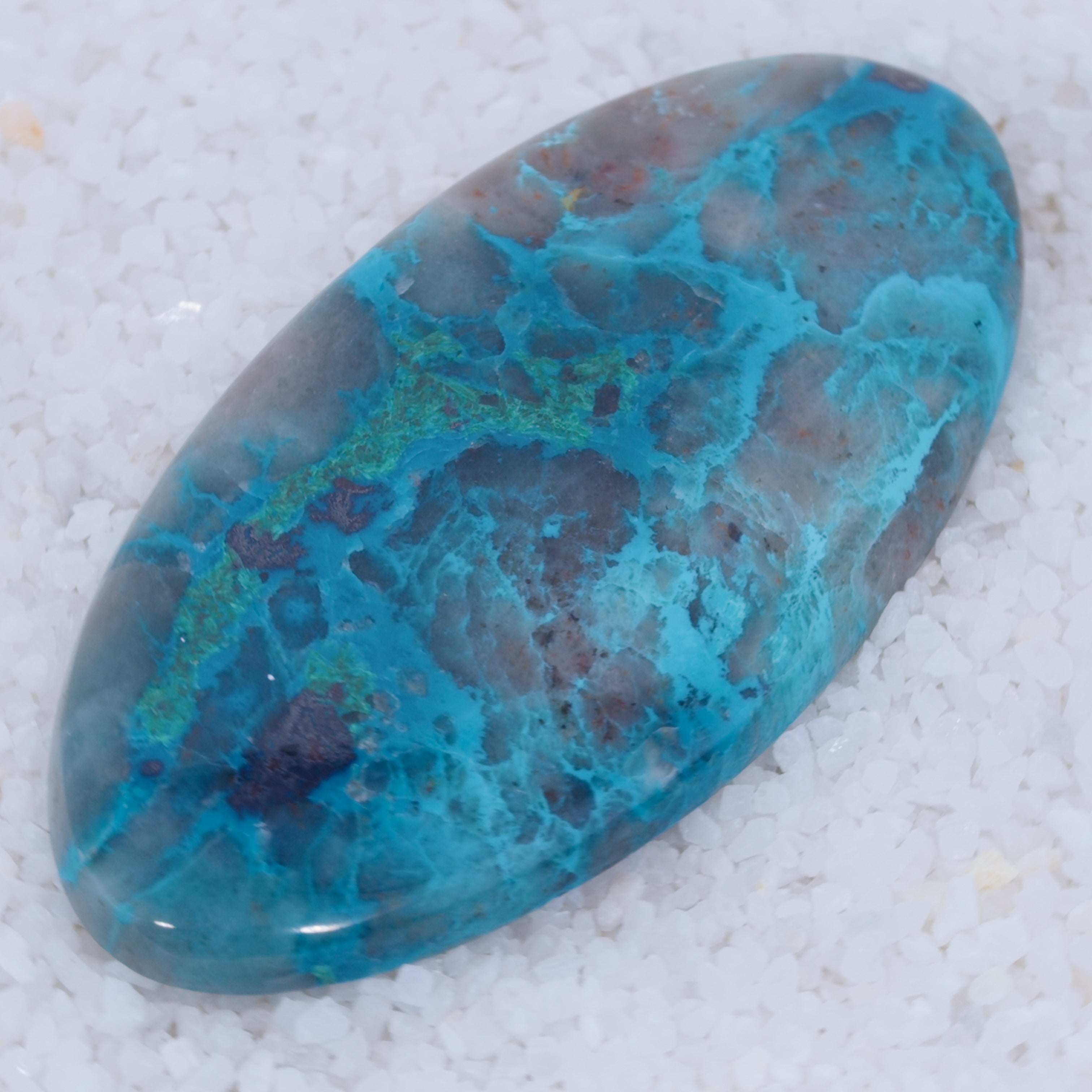 Turquoise colored Canyonite stone with blue and brown patterns on a white background