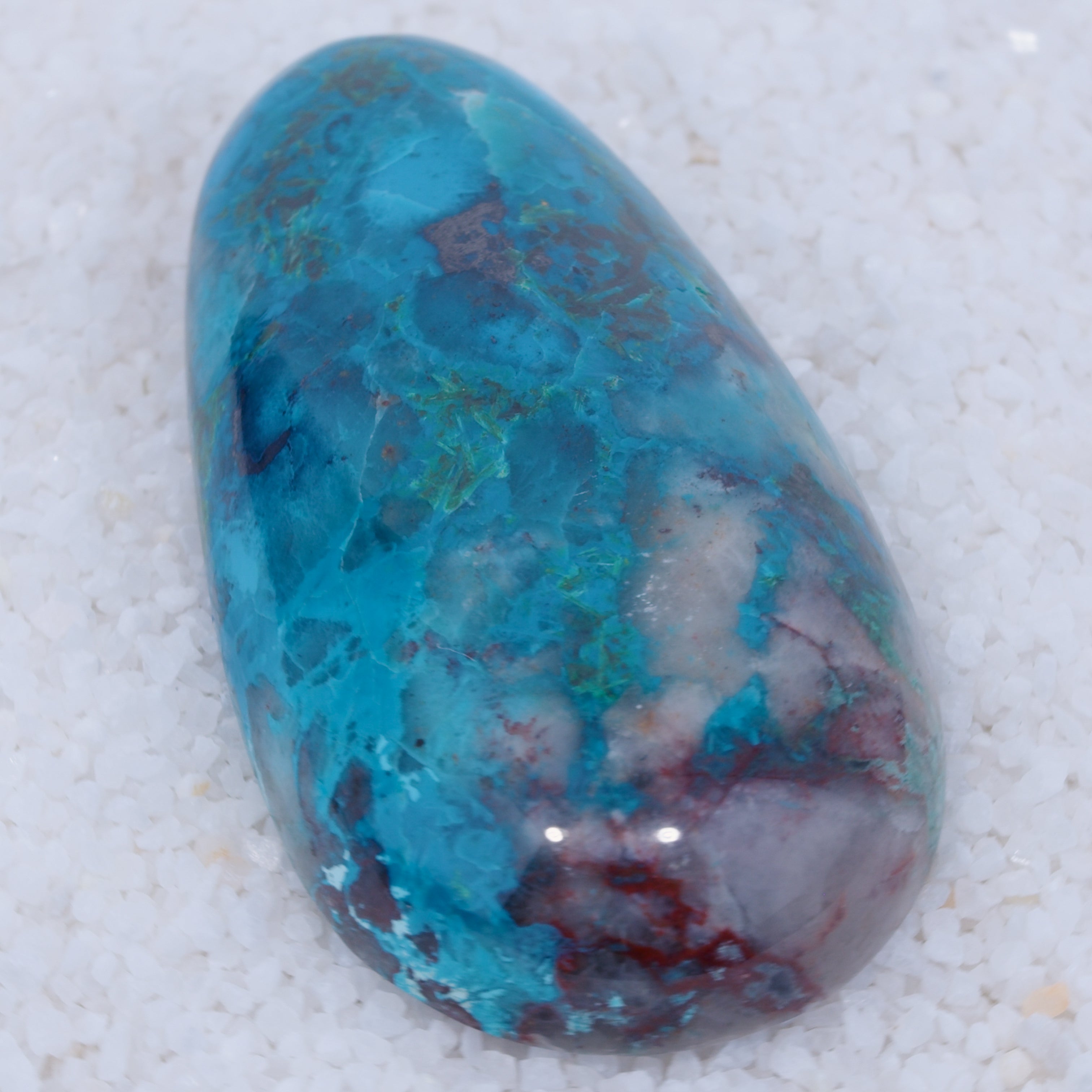 Polished Canyonite gemstone with blue, green, and red patterns on a white background
