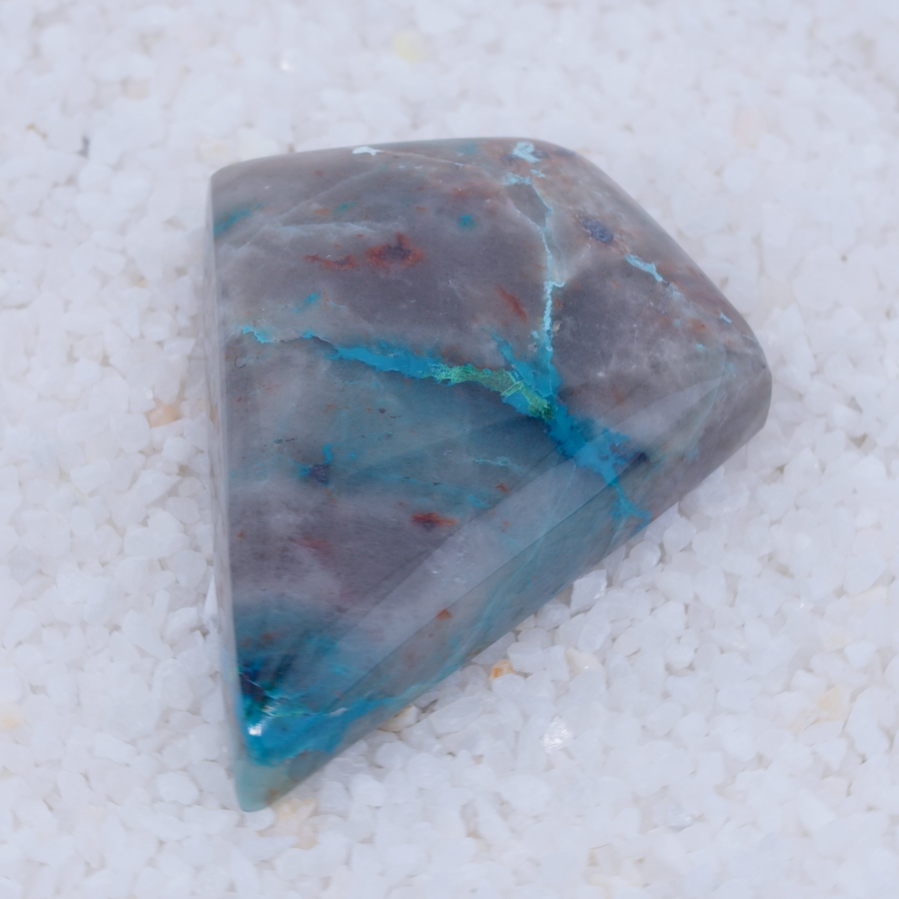 Polished Canyonite stone with blue and red inclusions on a white background