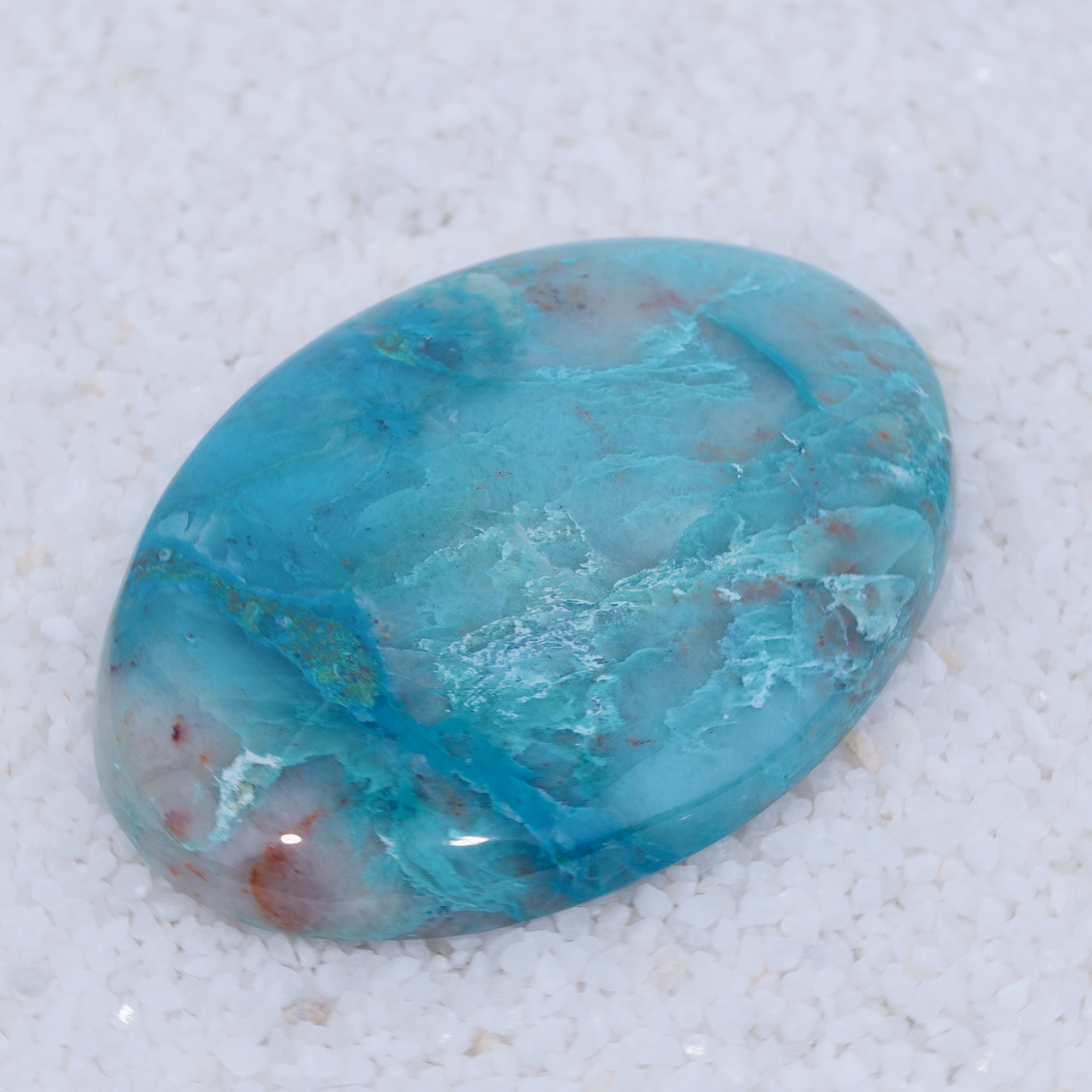 Turquoise color Canyonite stone on a textured white background
