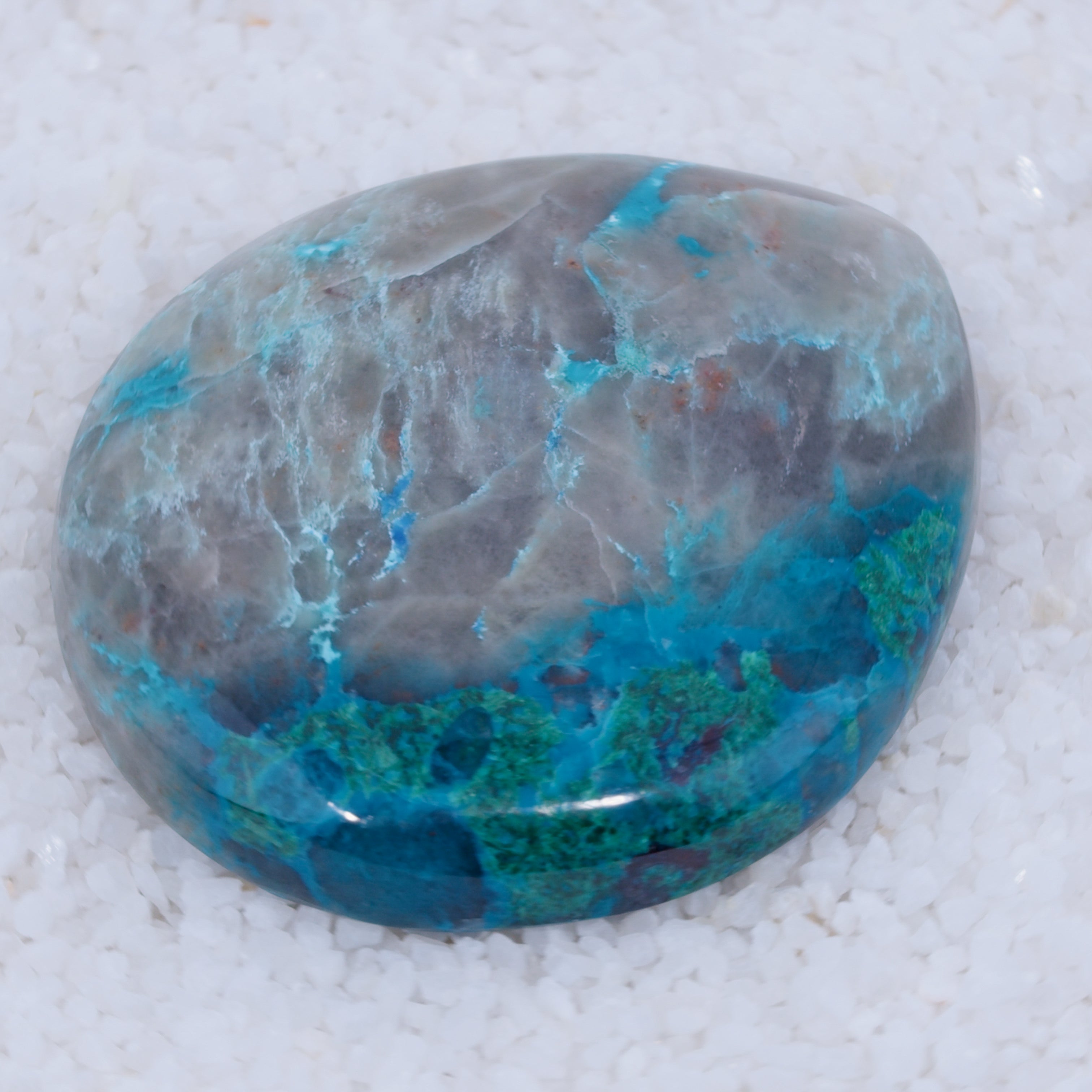 Polished stone with blue and green patterns on a white background