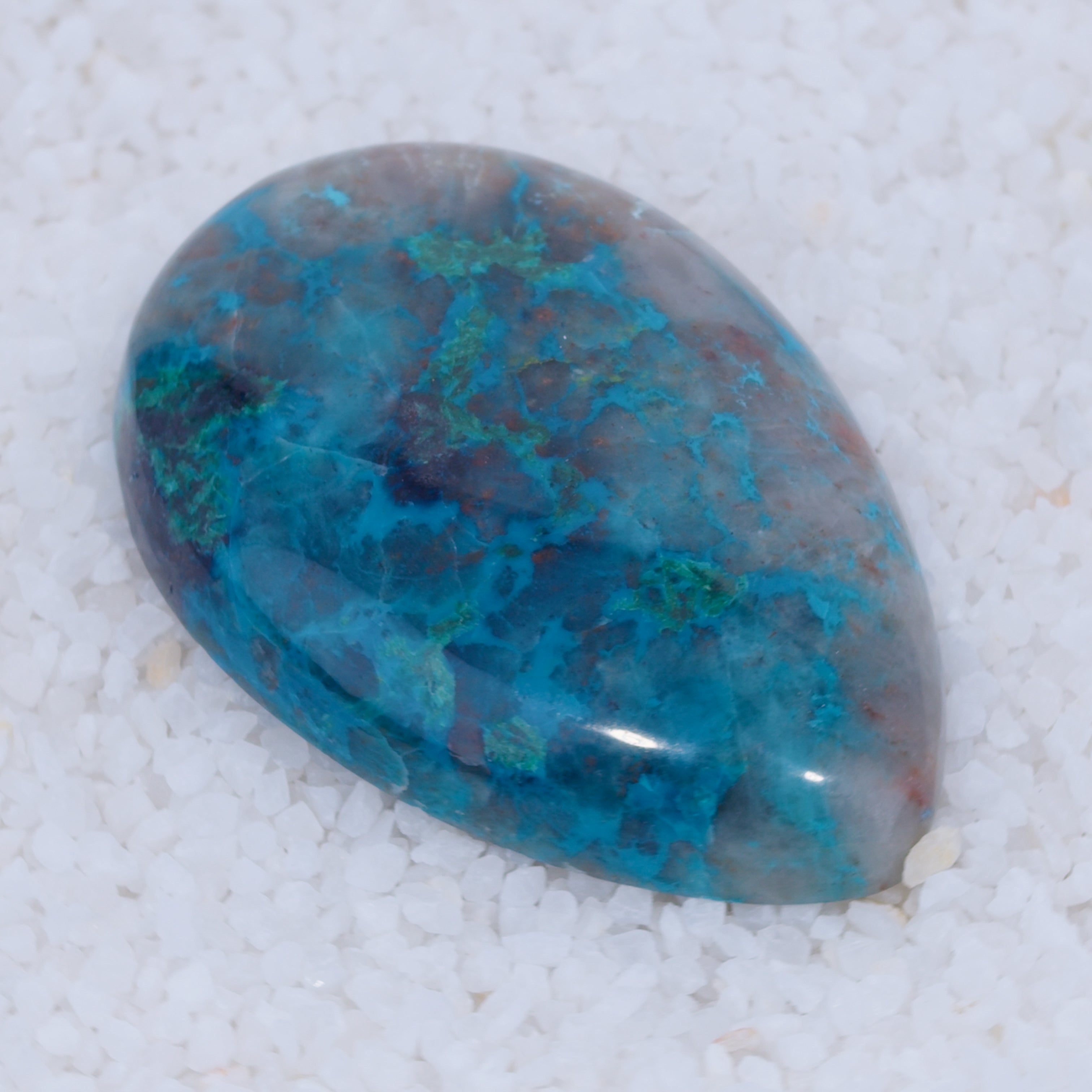 Oval-shaped Canyonite gemstone with blue and purple patterns on a white background