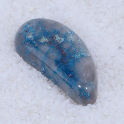 Crystal Canyonite with blue and red inclusions on a white sandy background