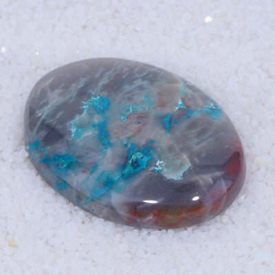 Polished Canyonite stone with blue and red mineral inclusions on a white background