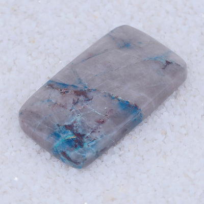 Rectangular Canyonite stone with blue and purple veins on a light gray background
