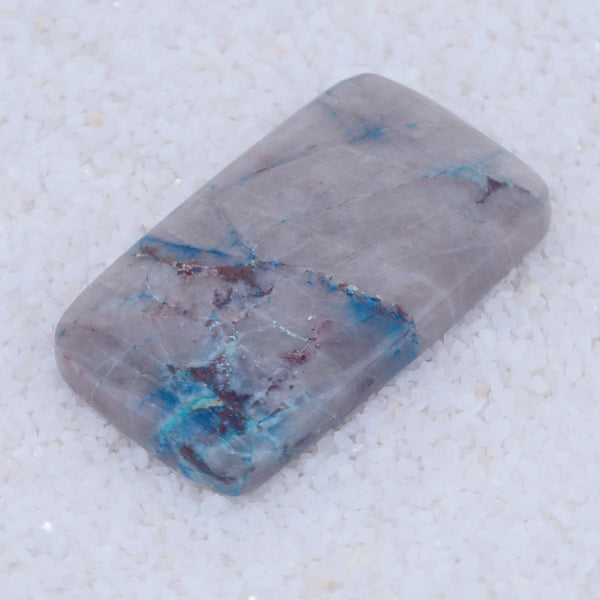 Rectangular Canyonite stone with blue and purple veins on a light gray background