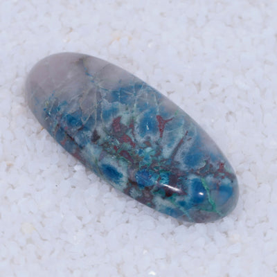 Marbled Canyonite stone with blue, green, and red patterns on a white background