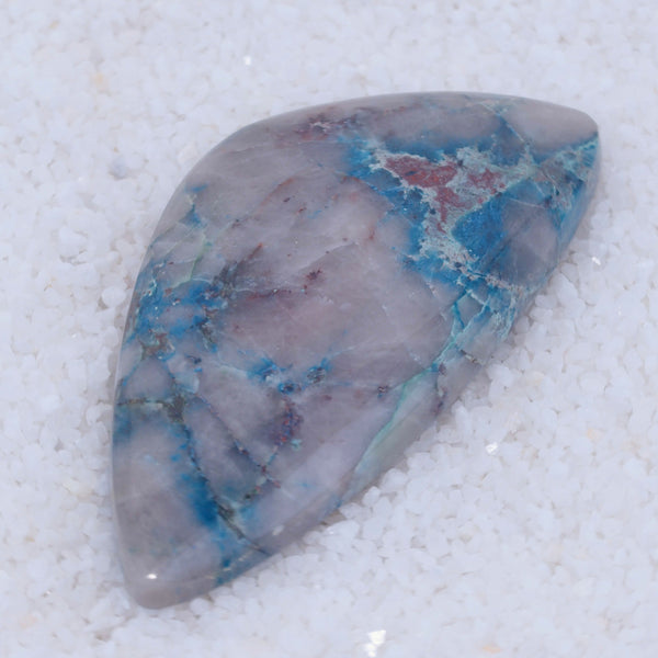 Polished Canyonite stone with blue and red patterns on a white background