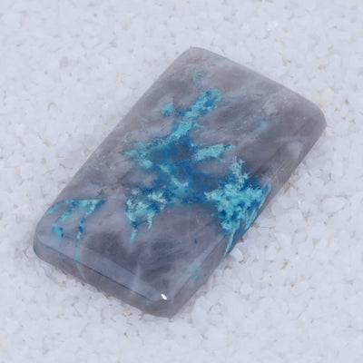 Rectangular Canyonite stone with blue and gray colors on a textured white background