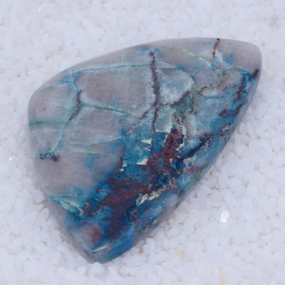 Triangular Canyonite stone with blue and purple patterns on a white background