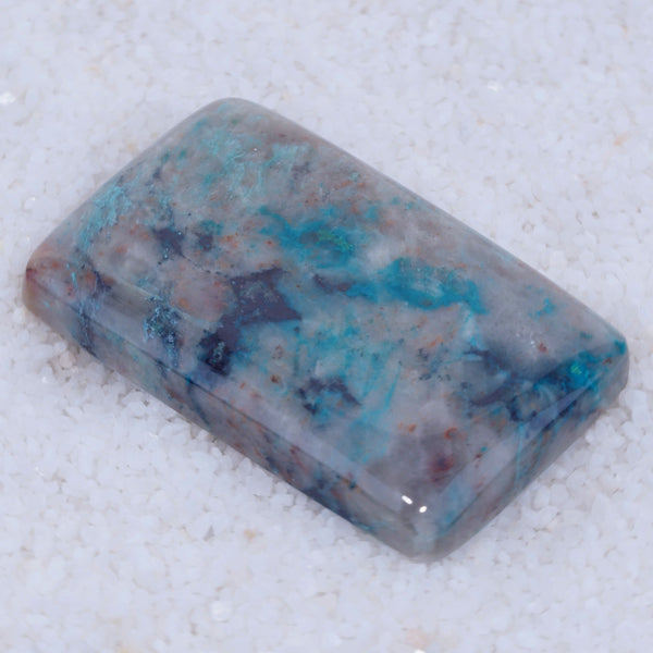 Rectangular Canyonite stone with blue and purple patterns on a white background